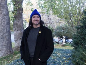 Photo of David standing in a garden and proudly wearing a blue beanie